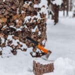 The 5 Best Log Splitters for Tippah County Firewood Season Axe stuck in a snow-dusted woodpile with stacked firewood