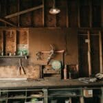The 5 Best LED Shop Lights for Tippah County Garages and Barns Rustic barn workshop interior with a wooden workbench, hand tools hanging on a pegboard wall, and an overhead shop light from the rafters