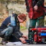 The 5 Best Generators for Power Outages in Tippah County Two men servicing a red portable gasoline generator outside during a power outage