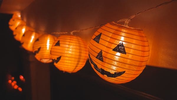 A string of jack-o'-lantern lights hanging beside a wall