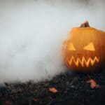 The 5 Best Fog Machines for Tippah County Halloween Haunts A carved jack-o'-lantern sits amid dense, low-lying fog in a dark Halloween yard — the spooky ground-fog effect a fog machine and low-lying fog fluid create.