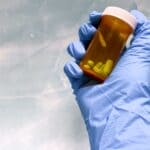 NMPHC Acquires Ashland Drugs, Reopening as NMPHCRx Gloved hand holding an amber prescription bottle, illustrating the Ashland Drugs pharmacy transition to NMPHCRx