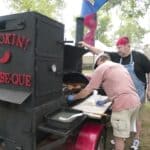 Bolivar BBQ Blowout Winners: Will Be Que BBQ Repeats Competition barbecue team tending meat on a large trailer smoker, illustrating the Bolivar BBQ Blowout winners story