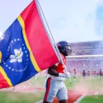 Mississippi News Report — Thursday, Oct 15: Ole Miss vs Missouri Ole Miss football fan primer graphic for the Missouri game — an athlete carries a large flag across a football field during a game.