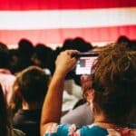 Mississippi News Report — Oct 22: Trump Rally, Wiley Case, Kratom Crowd at an indoor rally photographing an American flag, illustrating the confirmed Trump rally in Corinth