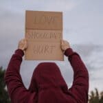 Hardeman County Marks Domestic Violence Awareness Month Person holding a 'Love should not hurt' sign, illustrating Hardeman County domestic violence awareness