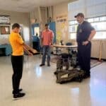 Ripley Middle School Community Helpers Week Hosts Firefighters Firefighter shows his turnout gear to a student during Ripley Middle School Community Helpers Week