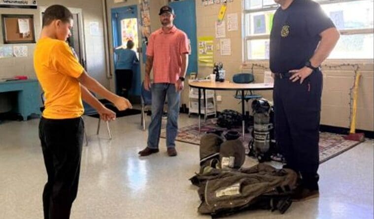 Firefighter shows his turnout gear to a student during Ripley Middle School Community Helpers Week