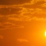 Tippah County Heat: Near-Record Low 90s Expected This Week Bright sun in an orange sky illustrating Tippah County heat forecast