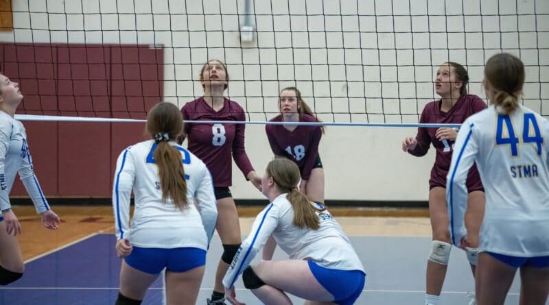 High school girls volleyball players at the net during an indoor match, illustrating the Tippah County volleyball all-tournament team