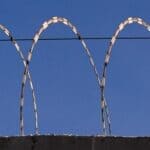 Two Inmates Die at Whiteville Correctional Facility Barbed wire atop a concrete wall, illustrating the Whiteville Correctional Facility story